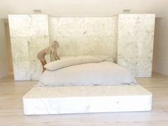 a bed with pillows on top of it in a room filled with white walls and wooden floors