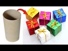 several wrapped presents sitting next to a toilet paper roll and a cup with a red ribbon