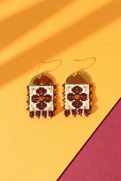 two pairs of beaded earrings on top of a yellow and red background with the letter e