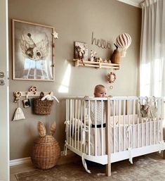 a baby in a crib next to some pictures on the wall