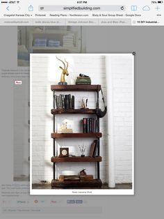 a book shelf with books and other items on it in front of a white brick wall