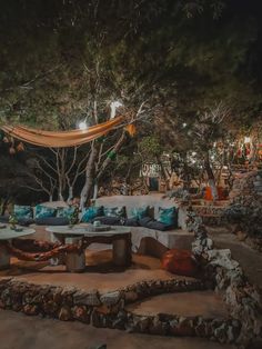 an outdoor seating area is lit up at night with lights shining on the trees and rocks