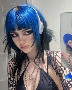 a woman with blue hair and headphones taking a selfie