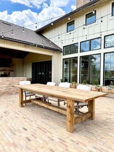 a wooden table sitting on top of a brick patio next to a large white building