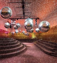 an empty stage with shiny balls hanging from the ceiling and steps leading up to it