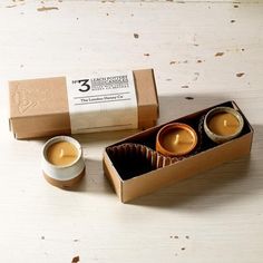 two small candles are sitting in a box next to each other on a wooden table