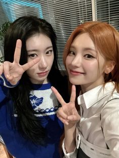 two young women posing for the camera with their fingers in the shape of peace signs