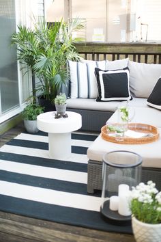 an outdoor living area with black and white striped rugs, wicker furniture, potted plants and candles