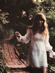 a woman in white dress standing on brick path