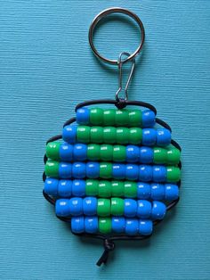 a blue and green beaded keychain is hanging on a blue surface,