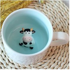 a small cow is sitting in a coffee cup filled with water and floating on top of it