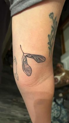 a woman's leg with a tattoo on it that has a flower and leaves