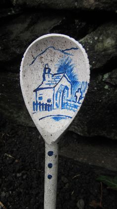 a white and blue spoon sitting on top of a dirt ground