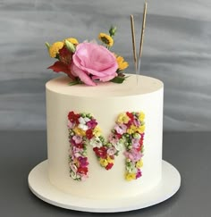 a white cake decorated with flowers and the letter m