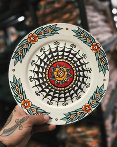 a hand holding a decorative plate with flowers on it