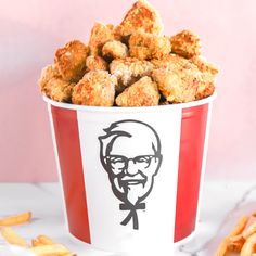 a bucket filled with fried food sitting on top of a white table next to magnets