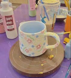 a cup sitting on top of a purple table next to other items and utensils