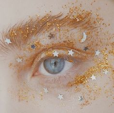 an eye with gold glitter on it and stars all over the place around its eyes