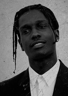 a man in a suit and tie with dreadlocks on his head looking at the camera