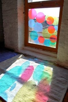 the sun is shining through a window onto a bed with colorful balloons on it in front of a brick wall