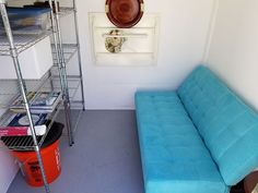 a blue couch sitting in the corner of a room next to a shelf with books