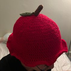 a woman wearing a red crocheted hat with a leaf on it