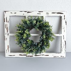 a white frame with a wreath hanging on it