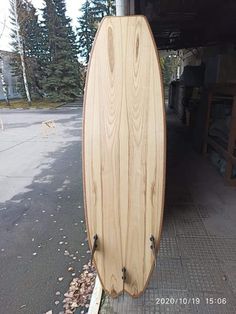 a wooden surfboard sitting on the side of a road