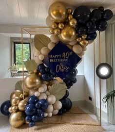 a birthday balloon arch with gold, black and white balloons