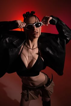 a woman in a black top and leather jacket posing for the camera with her hands on her hips