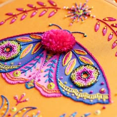 a close up of a decorative butterfly on an orange surface with pink flowers and leaves