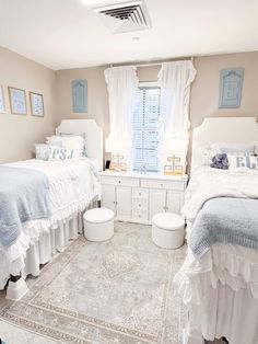 two twin beds in a bedroom with white furniture and blue decor on the wall above them