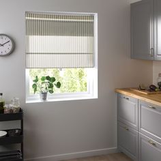 a kitchen with a clock on the wall next to a window and counter top in front of it