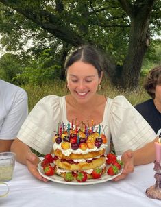 a woman sitting at a table with a cake in front of her