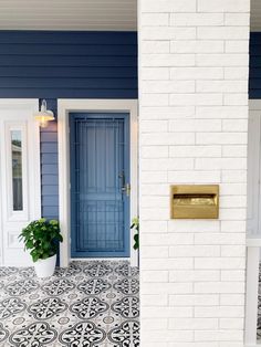 a blue front door with a white brick wall and black and white tile on the floor