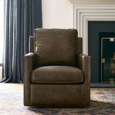 a brown chair sitting in front of a fire place next to a rug and window