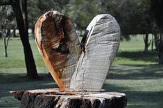 a heart shaped piece of wood sitting on top of a tree stump in a park