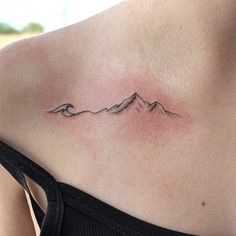 a woman with a tattoo on her chest that has mountains in the background and waves coming out of it