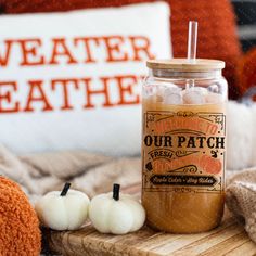 a jar filled with candy sitting on top of a wooden board next to two white pumpkins