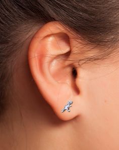 a close up of a person's ear with a small silver bird on it