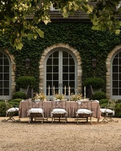 an outdoor dining table set up in front of two large windows