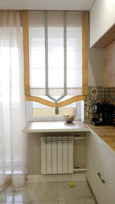 a small kitchen with white cabinets and wooden counter tops, along with a window covered in sheer curtains