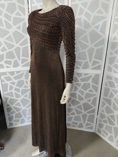 This late  1960s dress is so beautifully beaded with pinky brown pearls and bronze beads in a diagonal pattern on the bodice and they continue down the sleeves to wrist length. You would be sure to get lots of compliments wearing this stunning dress The label is Vie Victoria Royal of Hong Kong from the 60s. The bronze lurex dress has a high neckline, fitted bodice and waist then skims the hips to an A line skirt to ankle length The dress has a back nylon zipper, has small shoulder pads to help w Fitted Beaded Maxi Dress For Evening, Beaded Fitted Maxi Dress For Evening, Brown Floor-length Maxi Dress For Evening, Glamorous Brown Party Dress, Elegant Brown Sequin Dress, Fitted Brown Evening Dress For Party, Brown Fitted Evening Dress For Party, Brown Fitted Evening Dress, Elegant Brown Maxi Dress For Evening