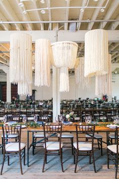 the tables and chairs are set up with chandeliers hanging from the ceiling above them