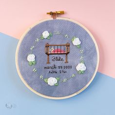 a cross stitch pattern with a baby's crib in the middle and flowers around it