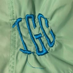 an embroidered jacket with the letter tgi on it's chest and blue thread