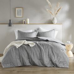 the bed is made with grey linens and pillows