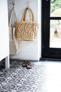 a pair of sandals sitting on the floor next to a door with a basket hanging from it