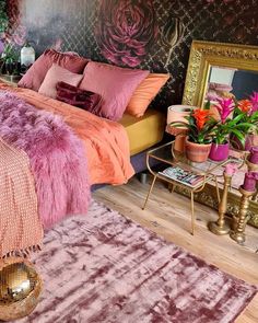 a bedroom decorated in pink and gold with a large bed covered in purple furs