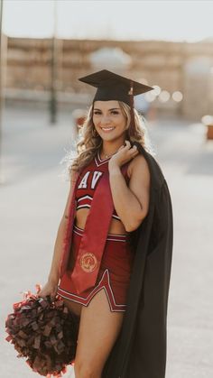 a woman in a graduation cap and gown holding a cheerleader pom pom